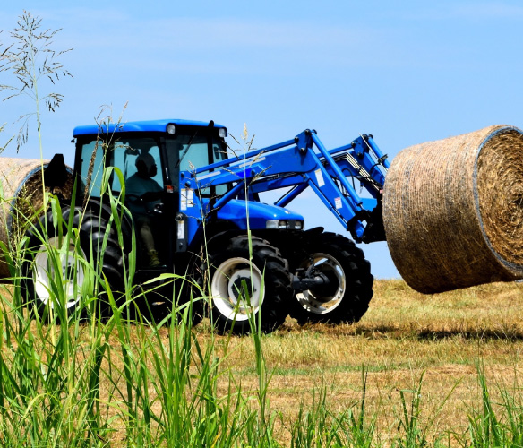 Ford/New Holland tractor with hay bale in the a field